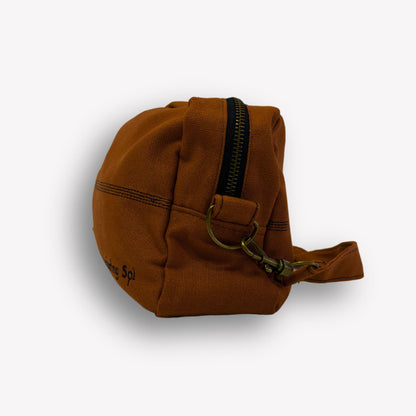 Side view of Clay Brown Crossbody Bag by Wandering Sol showing brown and bronze zip detail – made from recycled canvas with removable strap, can be worn as a clutch or shoulder bag.