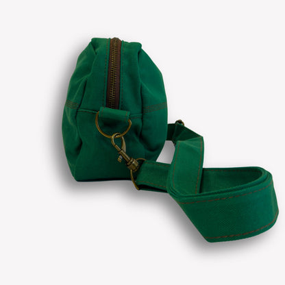 Side view of Emerald Green Crossbody Bag by Wandering Sol showing brown and bronze zip detail – made from recycled canvas with removable strap, can be worn as a clutch or shoulder bag.