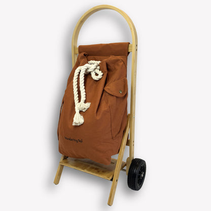 Side profile of Nimble Market Cart in Clay Brown showing slim bamboo frame, canvas bag, and forever wheels
