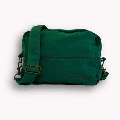 Front view of Emerald Green Crossbody Bag by Wandering Sol showing hardware bronze detail  – made from recycled canvas with removable strap, can be worn as a clutch or shoulder bag.